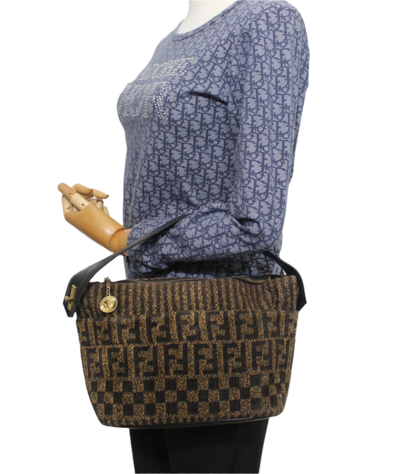 Brown patterned handbag held by a mannequin against a white background