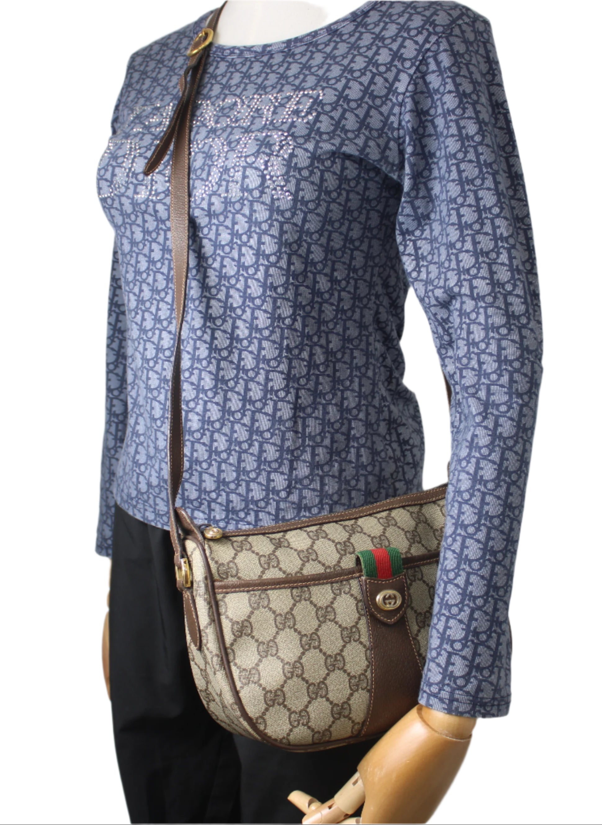 Mannequin wearing a blue patterned shirt with a Gucci handbag on a gray background