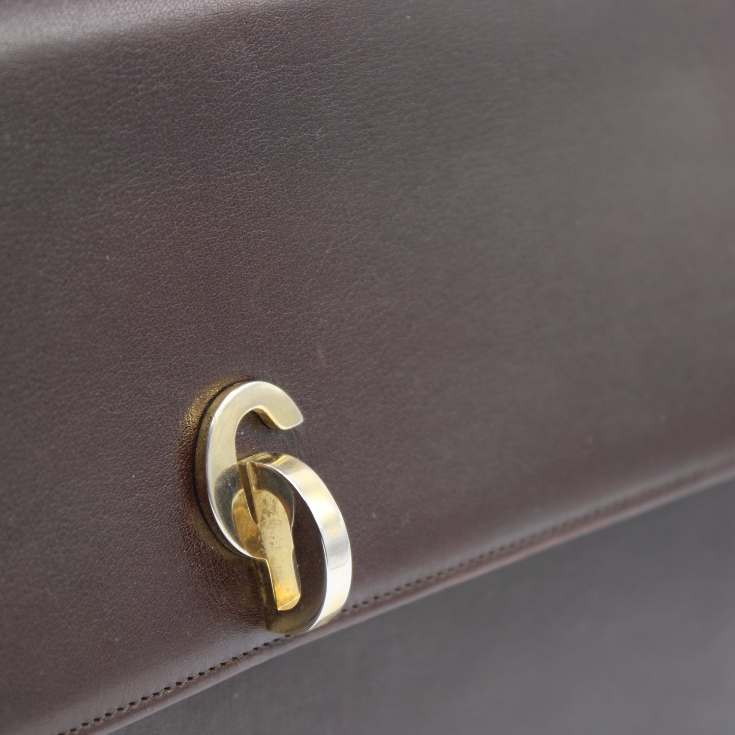 Close-up of a brown leather bag dior t with a gold CD elegant emblem.