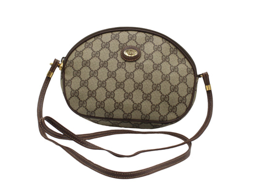 Brown patterned handbag with a strap on a light gray background Gucci Brown GG Canvas Oval Leather Trim Crossbody Bag