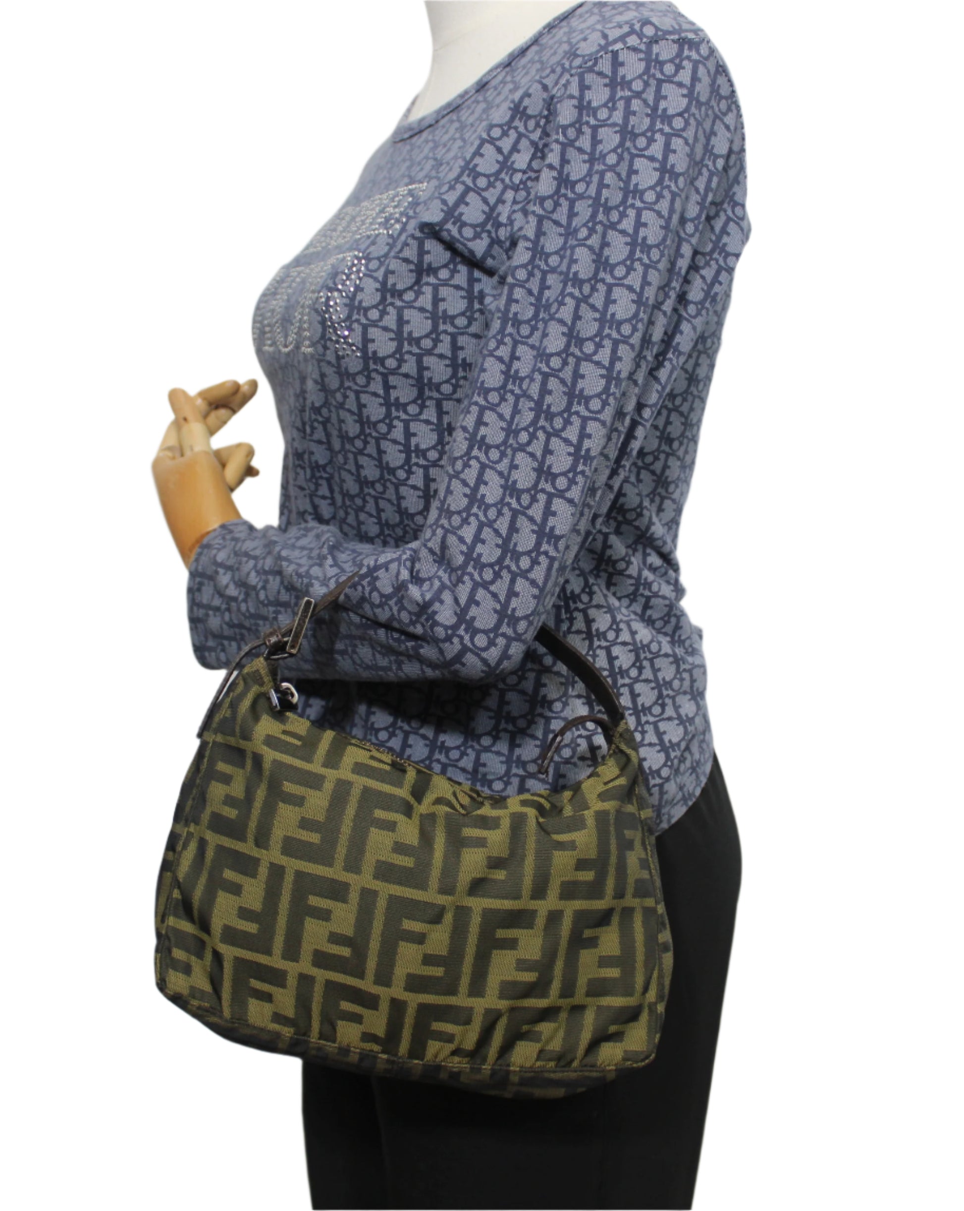 Mannequin wearing a blue patterned sweater with a green and brown handbag. Fendi Brown Zucca Canvas Mini Hand Bag