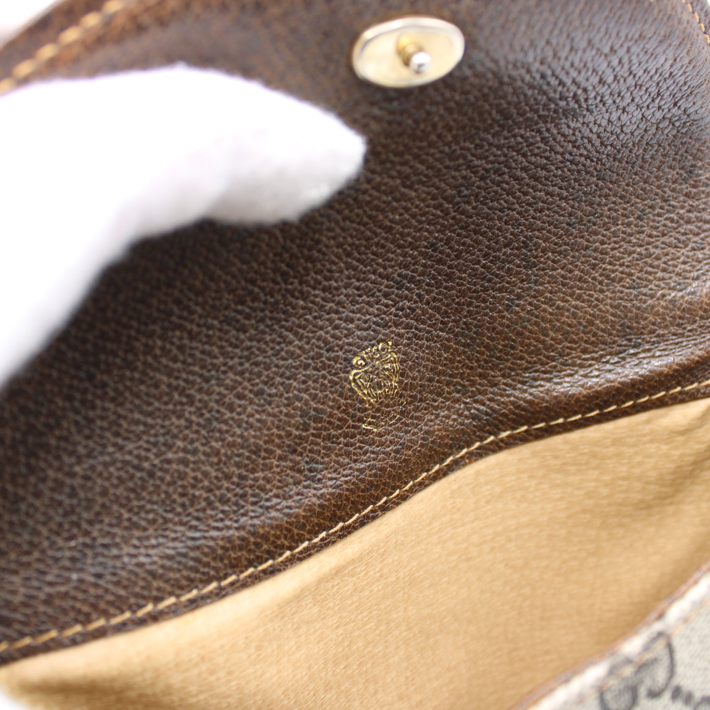Close-up of a brown leather product with a brand logo, likely a handbag or wallet.