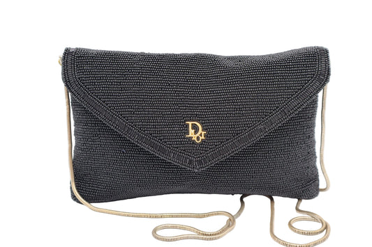 Christian Dior Black Beaded Gold Logo Chain Flap Bag A black beaded envelope clutch bag with a gold-tone Dior logo on the front flap and a matching gold chain strap, shown against a plain white background.