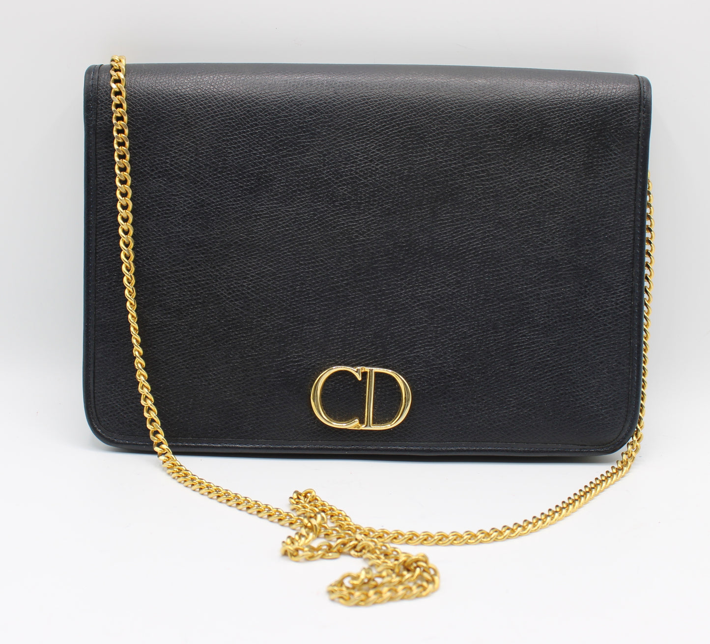 Black handbag with a gold chain on a white background Christian Dior Dark Navy Textured Leather Chain Crossbody Bag