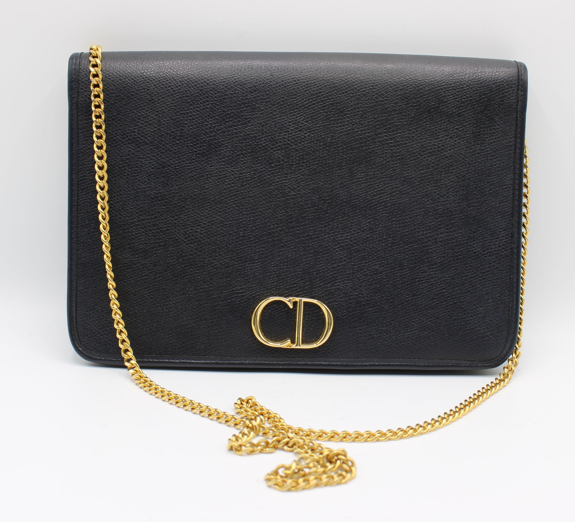 Black handbag with a gold chain on a white background Christian Dior Dark Navy Textured Leather Chain Crossbody Bag