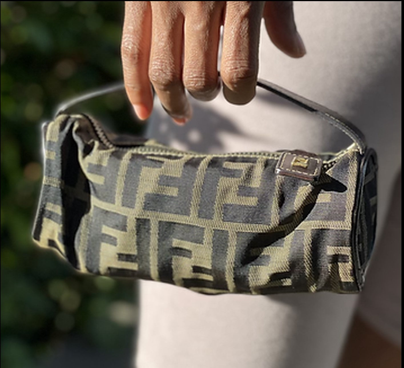 Hand holding a patterned handbag with a blurred background