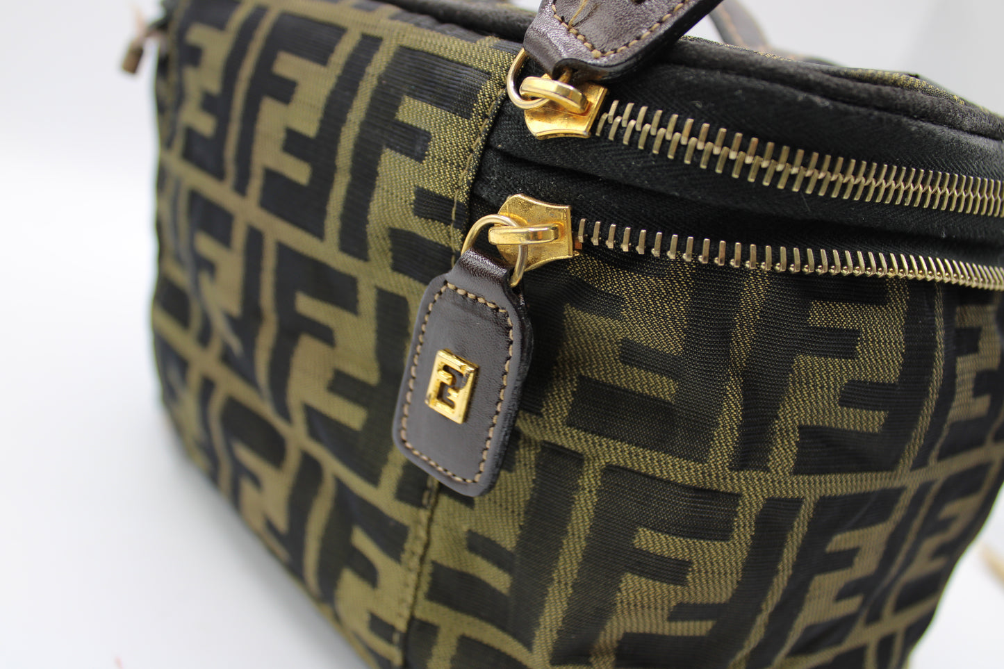 Green and black patterned bag with gold zippers on a white background