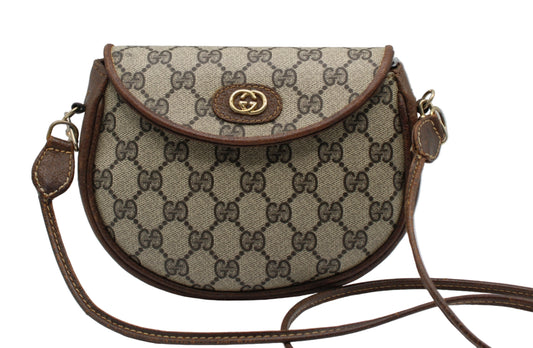Designer handbag with patterned fabric and brown leather accents on a light gray background