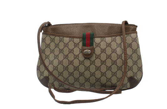Brown Gucci handbag with pattern and iconic stripe on a white background