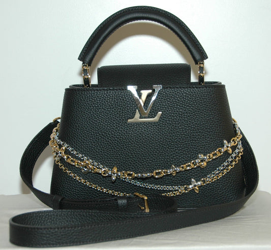 Louis Vuitton Black Taurillon Leather Capucines MM Chain On You Bag Black handbag with gold chain detail on a white surface