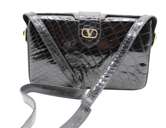 Valentino Garavani Black Croc Patent Leather Crossbody Bag Silver crocodile-patterned handbag with a gold logo on a white background